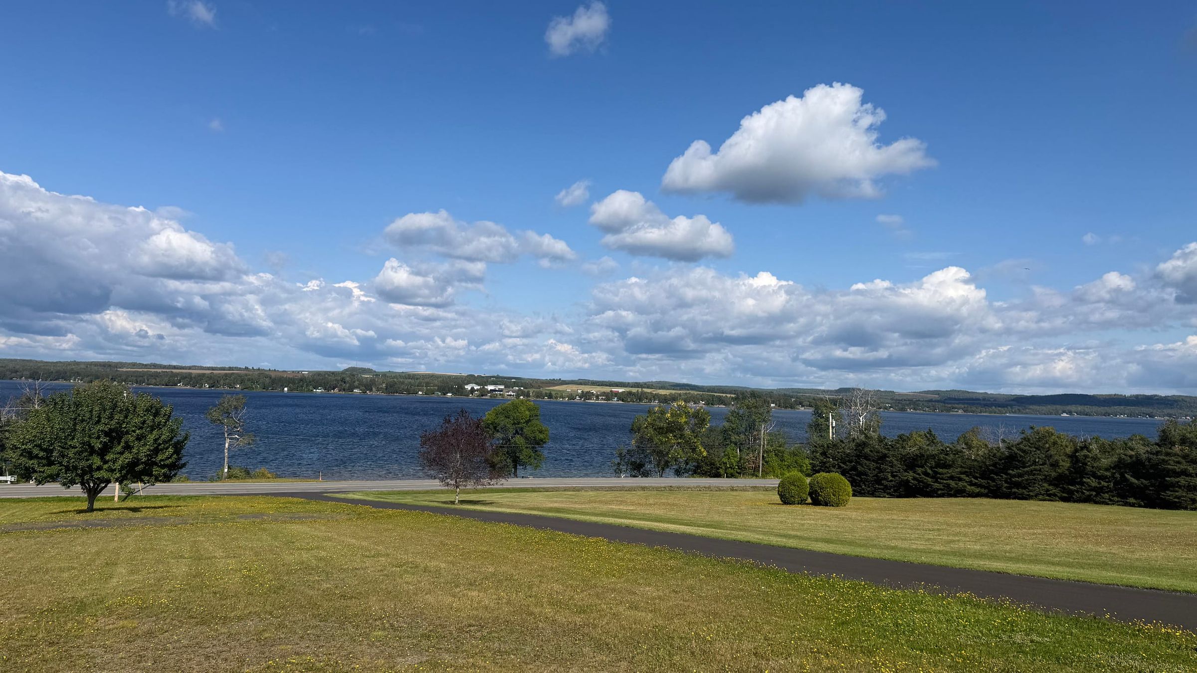 Green lawn running down to Long Lake under a blue summer sky